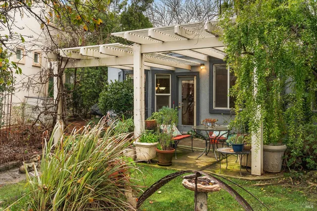 a view of a patio with table and chairs potted plants and floor to ceiling window