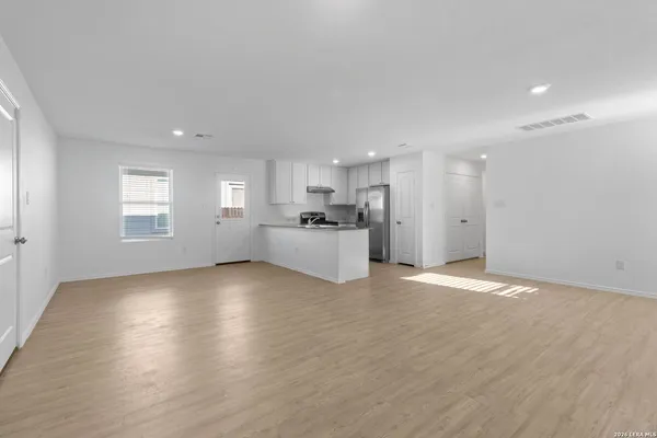 a view of a electric appliances in kitchen and empty room with wooden floor