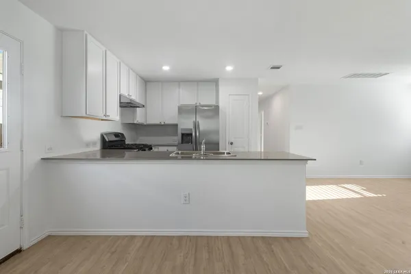 a view of kitchen with stainless steel appliances granite countertop cabinets and wooden floor