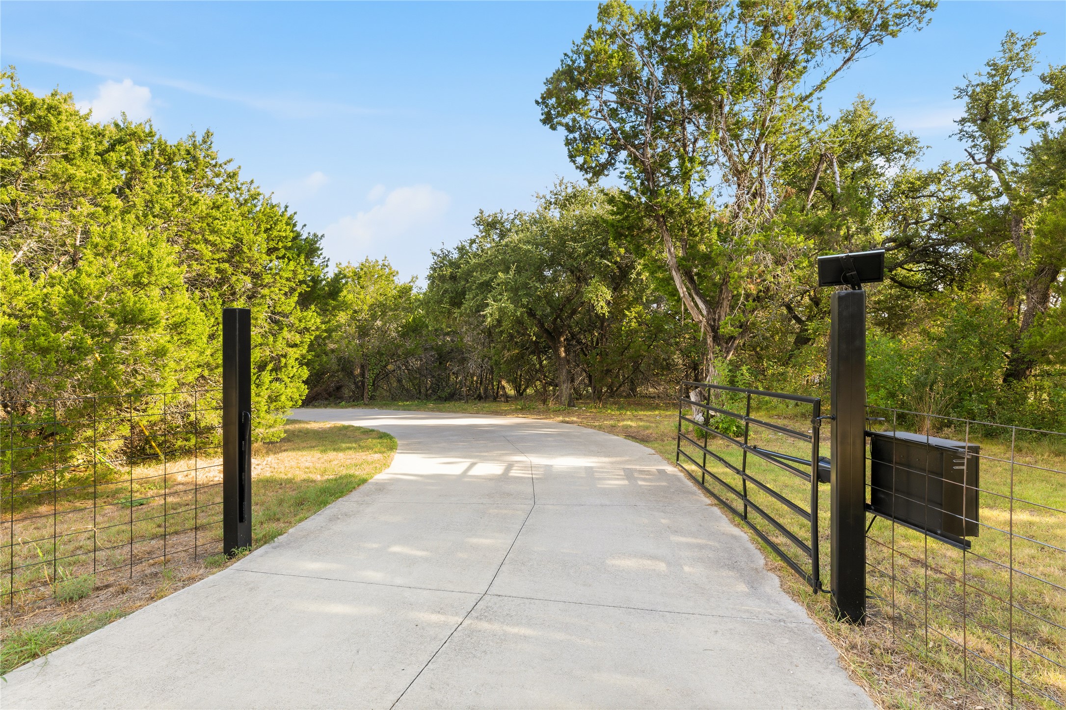 12901 Wire Road Leander, TX 78641 - Photo 38 of 40 Mature trees line the concrete driveway beyond a secure gated entrance.