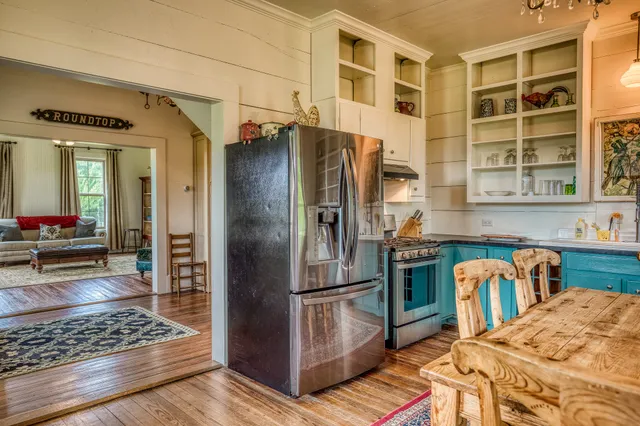 a kitchen with stainless steel appliances granite countertop a refrigerator a stove and a sink with wooden floors