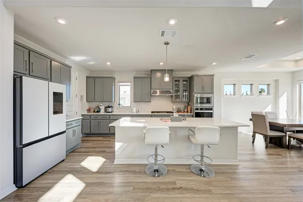 a large white kitchen with lots of counter space and stainless steel appliances