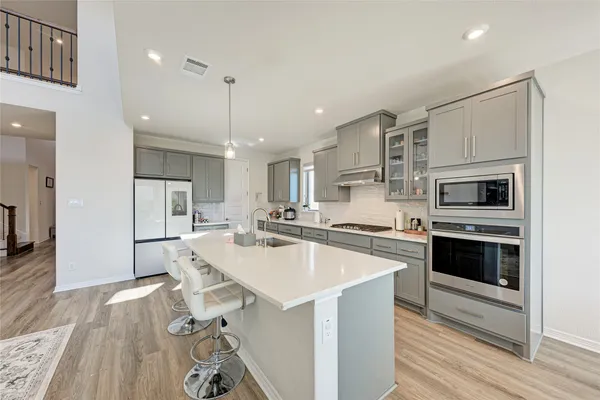 a kitchen with stainless steel appliances a stove top oven a sink dishwasher and a refrigerator
