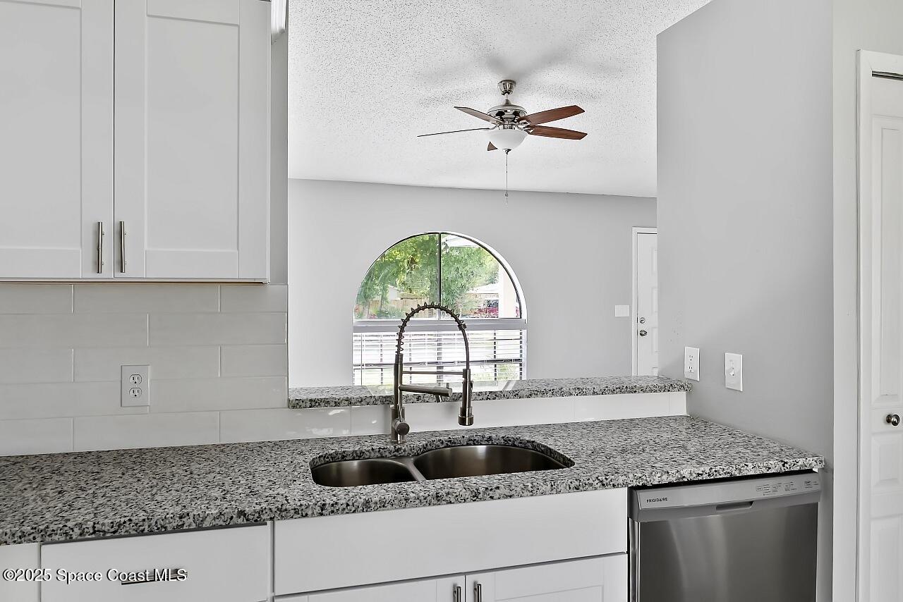 914 Devon Avenue Sebastian, FL 32958 - Photo 14 of 40 a kitchen with a granite countertop white cabinets white stainless steel appliances and a sink