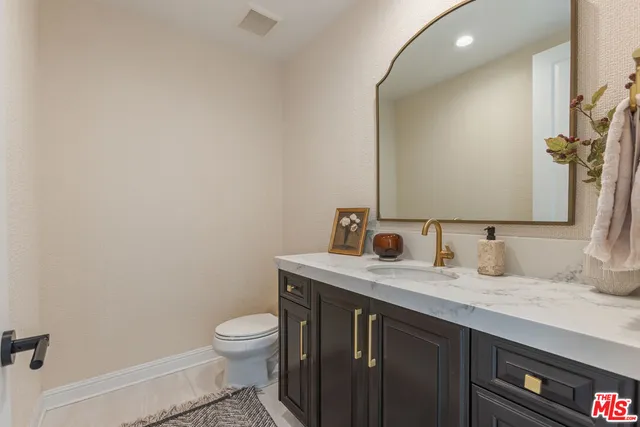 a bathroom with a granite countertop sink a toilet and a mirror