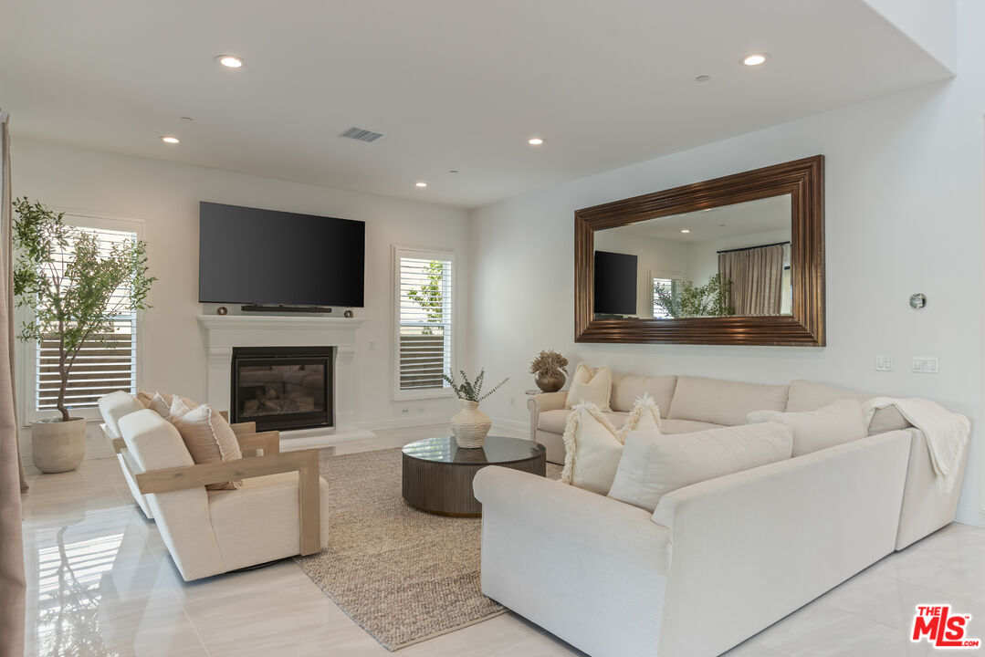 11734 Manchester Way Porter Ranch, CA 91326 - Photo 6 of 35 a living room with furniture a fireplace and a flat screen tv