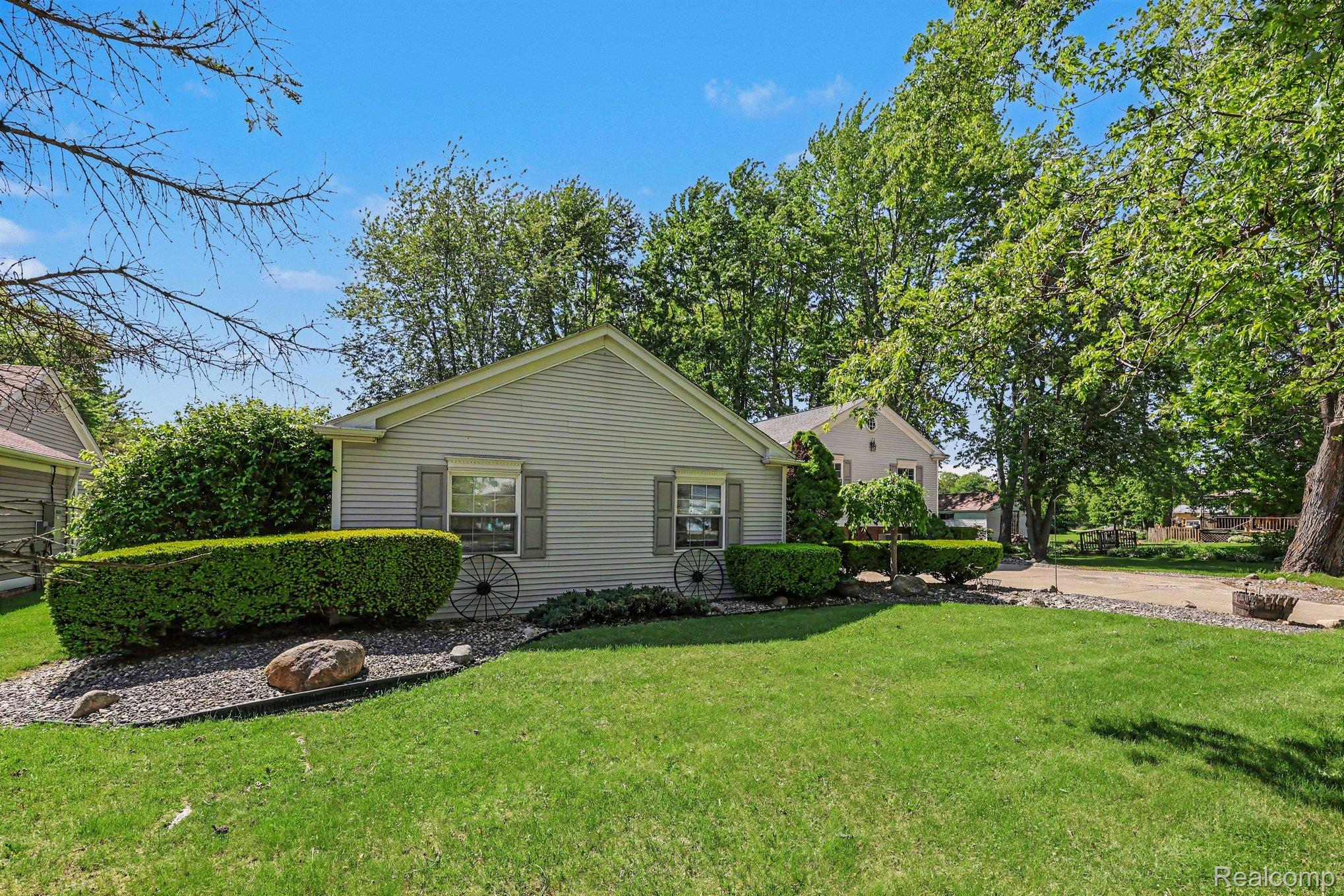 7020 Meldrum Road Fair Haven, MI 48023 - Photo 6 of 43 Gabled home exterior with horizontal siding, framed by mature trees and manicured landscaping
