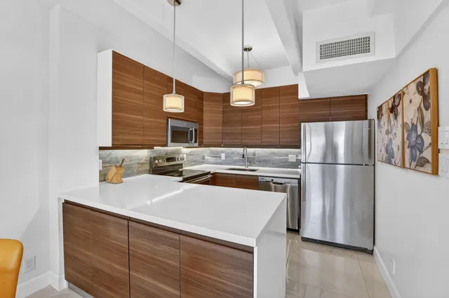 a kitchen with stainless steel appliances a refrigerator a sink a stove and white cabinets