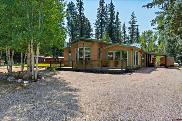 a view of a house with a yard and large trees