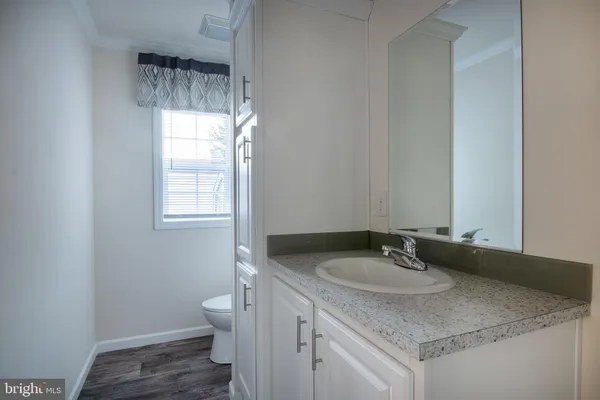 a bathroom with a granite countertop sink and a toilet