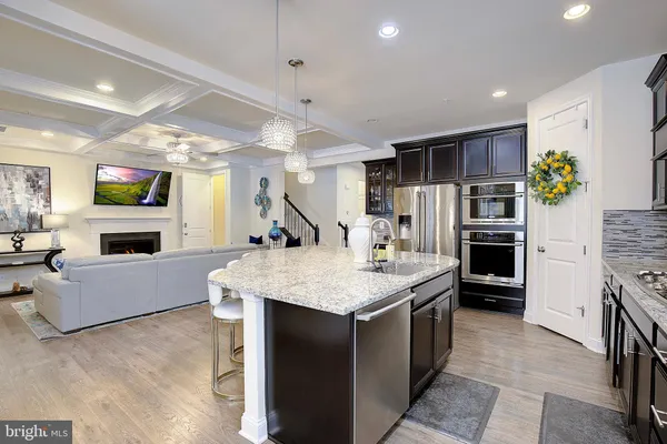 a large kitchen with stainless steel appliances kitchen island granite countertop a refrigerator a stove and a sink with wooden floor