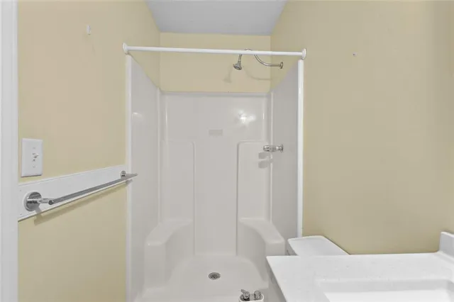 a bathroom with a sink a toilet a mirror and shower