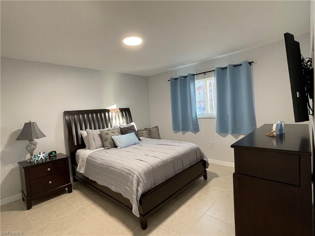 170 Turtle Lake Court, Unit 103 Naples, FL 34105 - Photo 14 of 37 a bedroom with a bed and flat screen tv