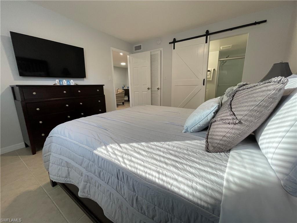 170 Turtle Lake Court, Unit 103 Naples, FL 34105 - Photo 15 of 37 a bedroom with a bed and a flat screen tv