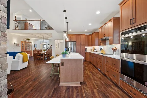 a kitchen with stainless steel appliances kitchen island granite countertop a stove a refrigerator a microwave oven with white cabinets and wooden floor