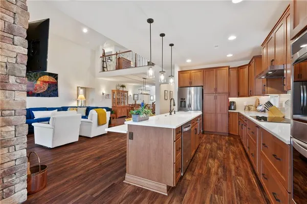 a kitchen with stainless steel appliances granite countertop a sink a stove and a wooden floors