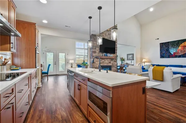 a kitchen with stainless steel appliances a stove top oven a sink dishwasher a dining table and chairs with wooden floor