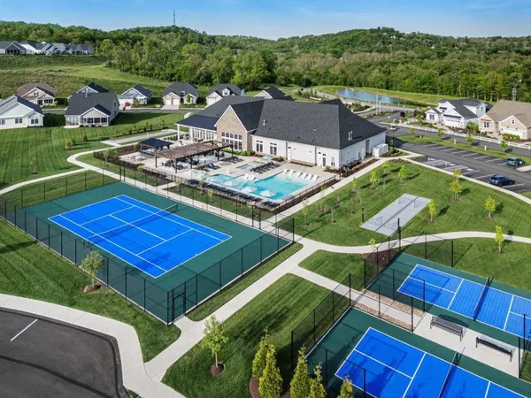 an aerial view of a tennis ground and a cars park side of the road