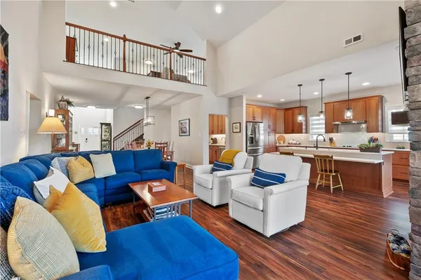 a living room with furniture kitchen view and a wooden floor
