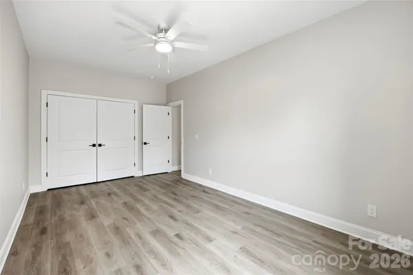 an empty room with wooden floor chandelier fan and windows