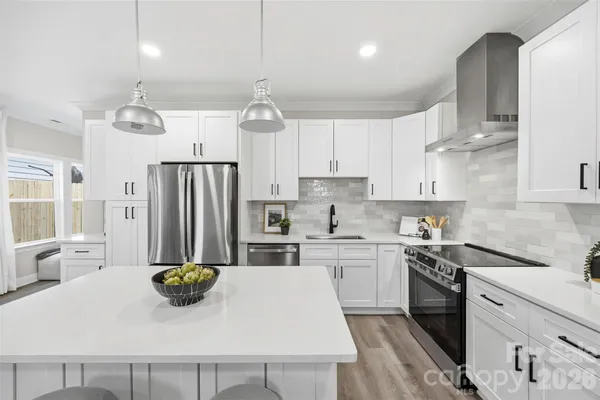 a kitchen with stainless steel appliances a dining table chairs sink and cabinets