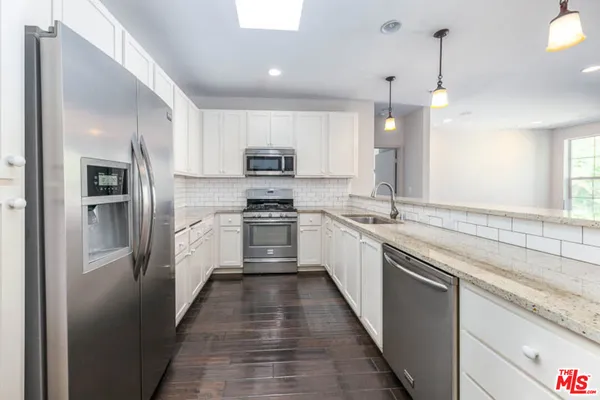 a kitchen with kitchen island granite countertop a sink appliances cabinets and a counter top space