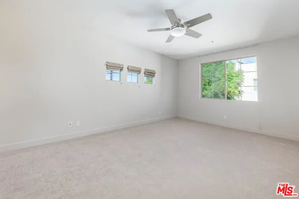 an empty room with windows and ceiling fan