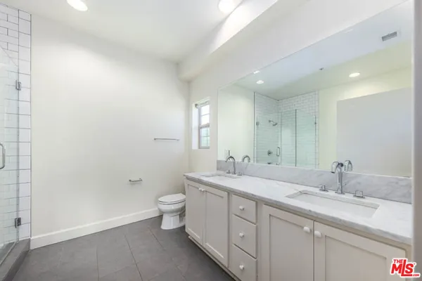 a bathroom with a double vanity sink toilet mirror and shower