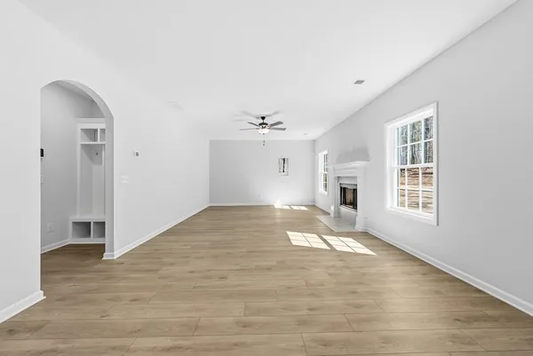 a view of empty room with wooden floor and fan