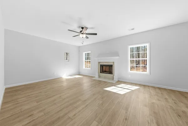 an empty room with windows fireplace and wooden floor