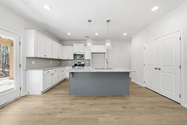 a large kitchen with kitchen island a sink a center island stainless steel appliances and a window
