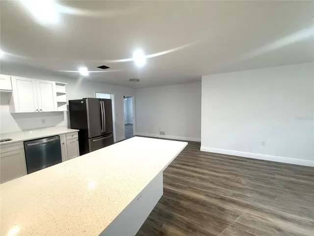 a large white bed in a kitchen with kitchen island stainless steel appliances cabinets a sink and a counter top space