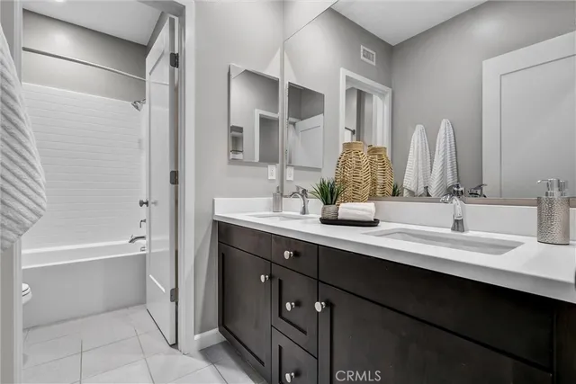 a bathroom with a double vanity sink a mirror a bathtub and shower