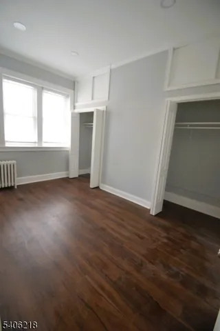 an empty room with wooden floor cabinet and windows
