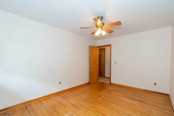 a view of a big room with wooden floor and a ceiling fan