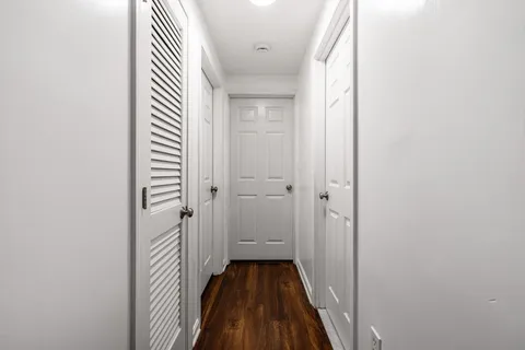 a view of a hallway with wooden floor and a bathroom