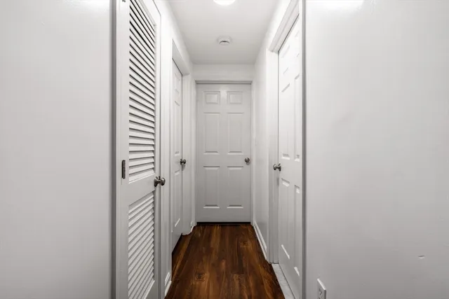 a view of a hallway with wooden floor and a bathroom
