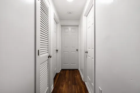 a view of a hallway with wooden floor and a bathroom
