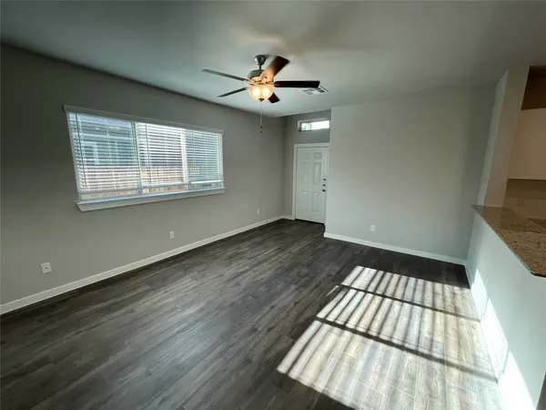 a view of an empty room with wooden floor and a window