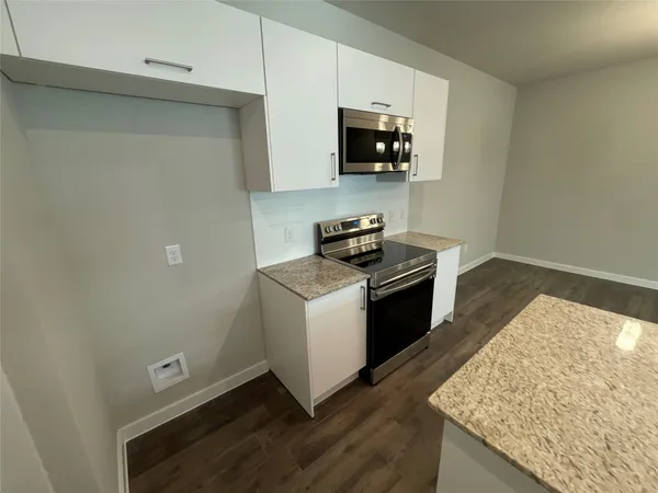 a kitchen with stainless steel appliances granite countertop a stove a sink and a microwave