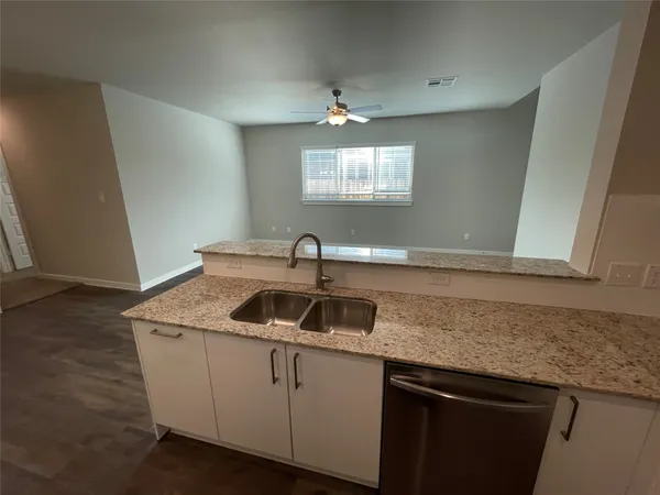 a kitchen with granite countertop a sink and dishwasher with wooden floor