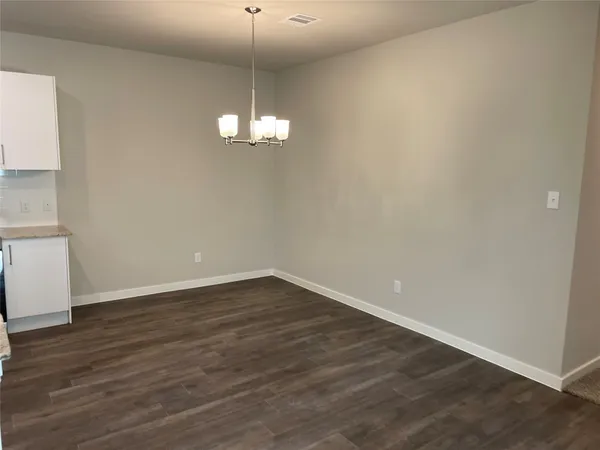 a view of empty room with wooden floor chandelier and window