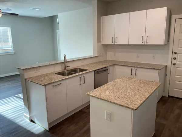 a kitchen with granite countertop white cabinets sink and dishwasher with wooden floor