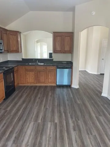 a large kitchen with cabinets wooden floor and stainless steel appliances