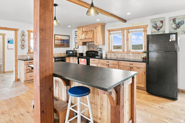 715 Ranch Loop Road Preston, ID 83263 - Photo 19 of 77 Kitchen featuring wood-finish cabinetry, dark countertops, and a central island with a breakfast bar