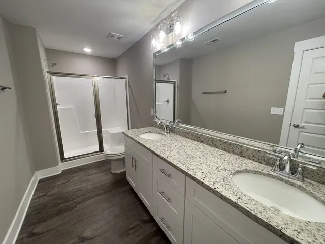 a bathroom with a granite countertop double vanity sink and a mirror