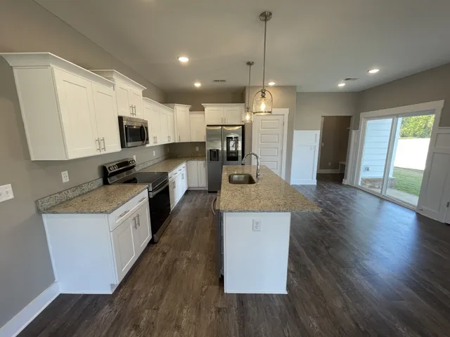 a large kitchen with kitchen island a stove a sink a center island and wooden floor