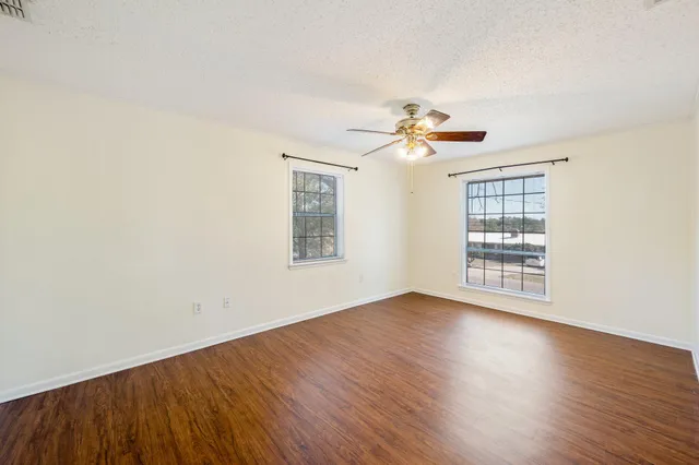 an empty room with wooden floor and ceiling fan