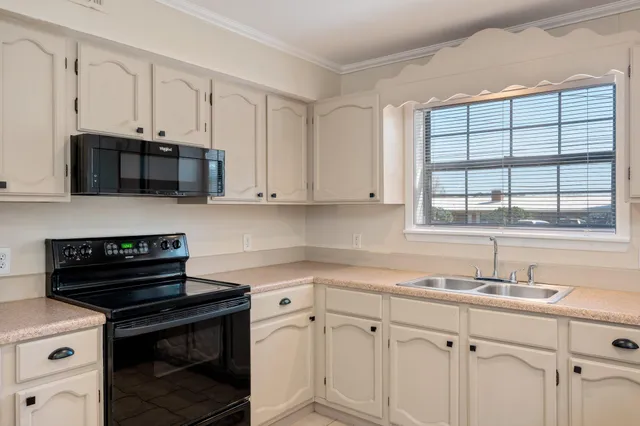 a kitchen with white cabinets and window