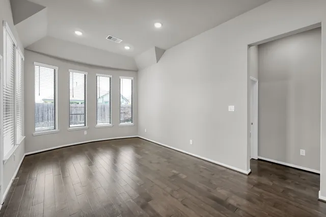 a view of an empty room with wooden floor and a window